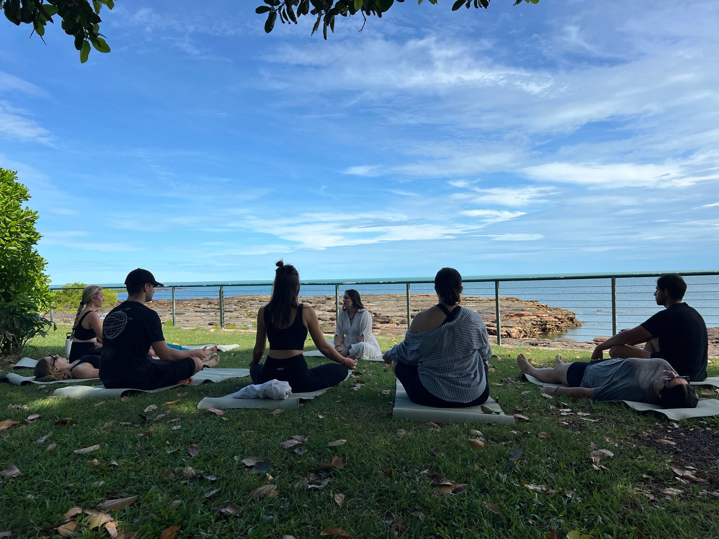 Meditazione di gruppo sul prato davanti all’oceano, a Darwin
